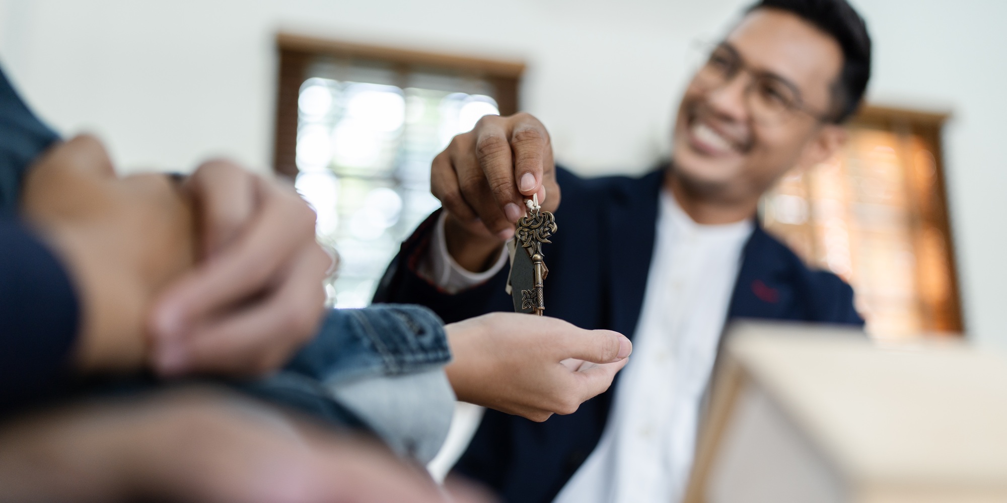 Happy real state agent giving new house key to a young couple. Real estate concept